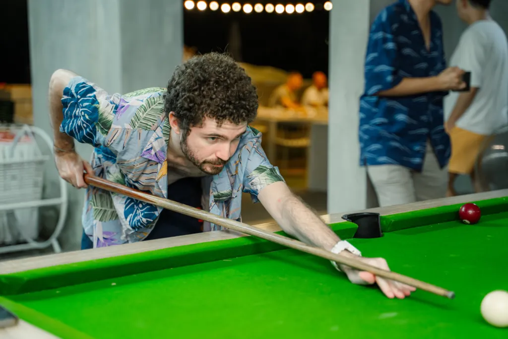 Man playing pool in a vibrant shirt