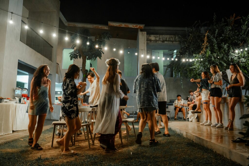 Outdoor evening party with string lights and guests dancing.