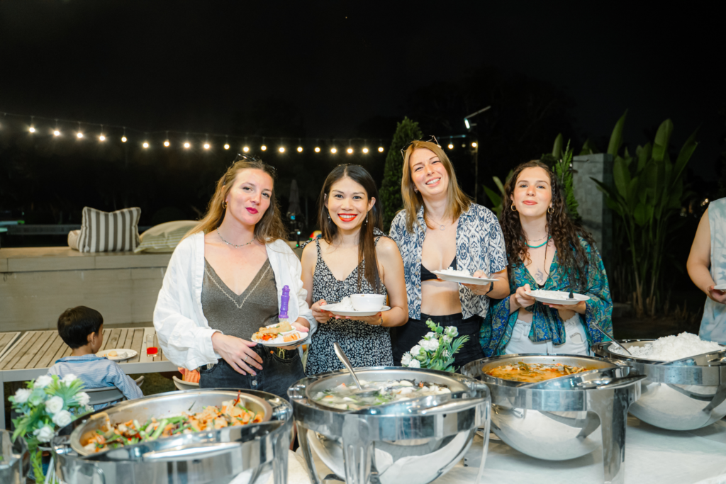 Women enjoying outdoor buffet at night event.