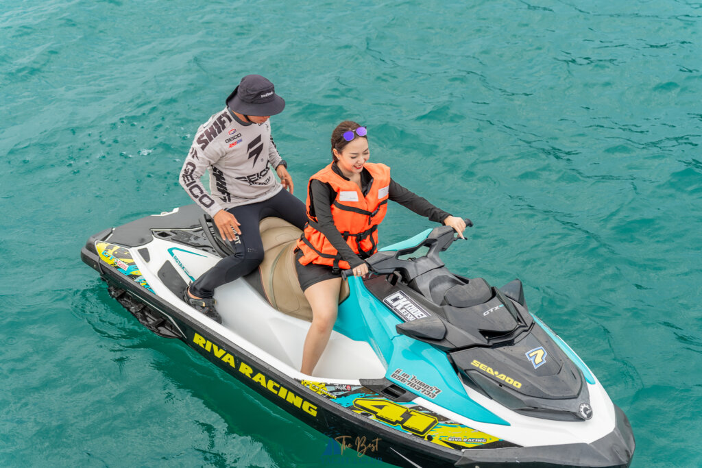Two people riding a jet ski on clear water.