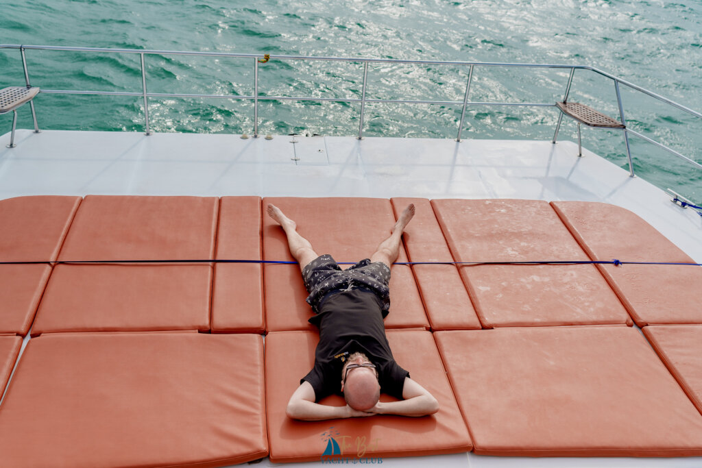 Person relaxing on yacht sun pad at sea.